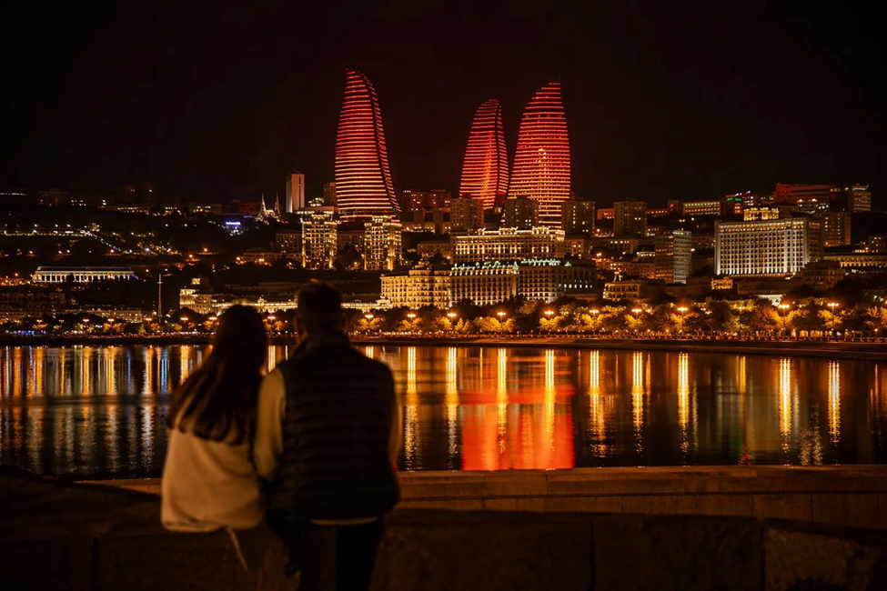 Baku Flame Towers illuminated at night reflected in Caspian Sea honeymoon destination Azerbaijan