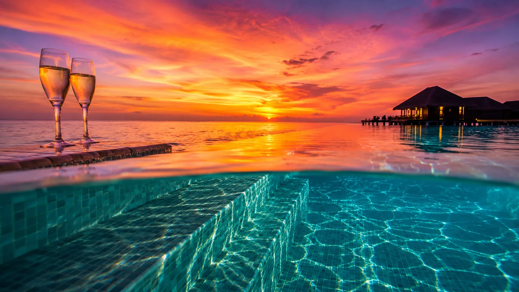 Infinity pool edge merging with the Maldives ocean at sunset | custom family trips planned by Zaviamo.