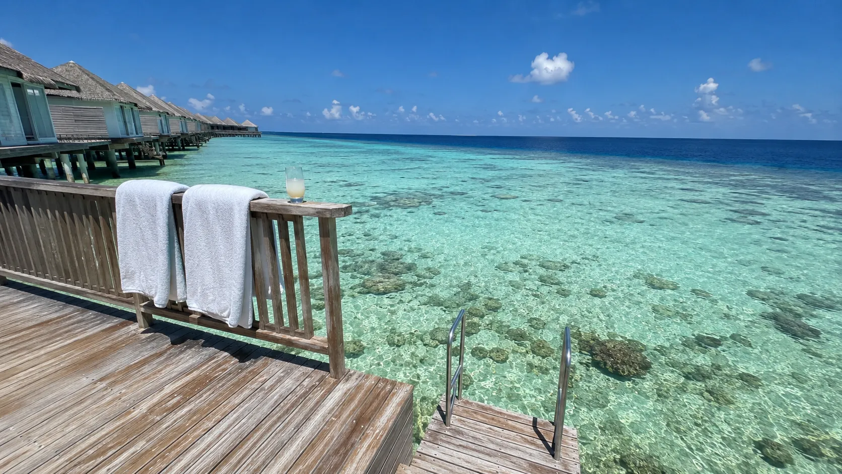 Private overwater villa deck in the Maldives at midday with crystal-clear turquoise lagoon and coral visible below | Maldives visa for Pakistanis
