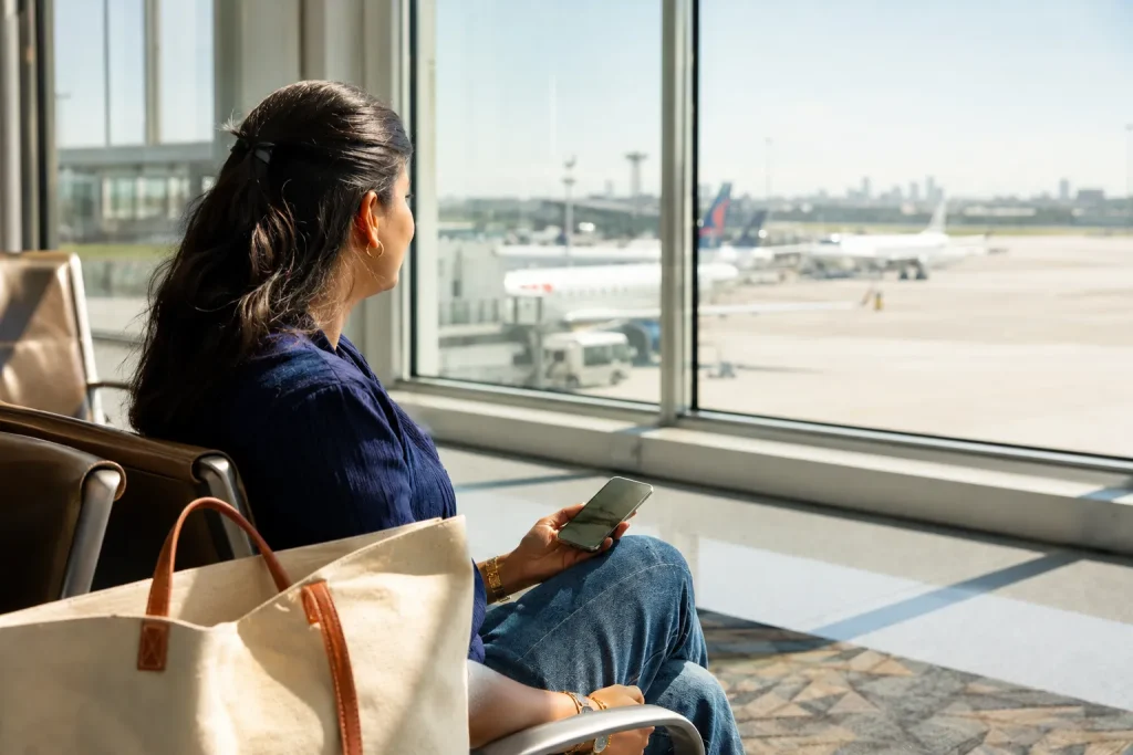 South Asian traveler at airport gate checking phone eSIM tips for summer travel 2026