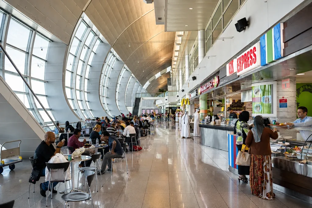 DXB airport food court with travellers dining, Dubai open for UAE Virtual Work Visa applicants