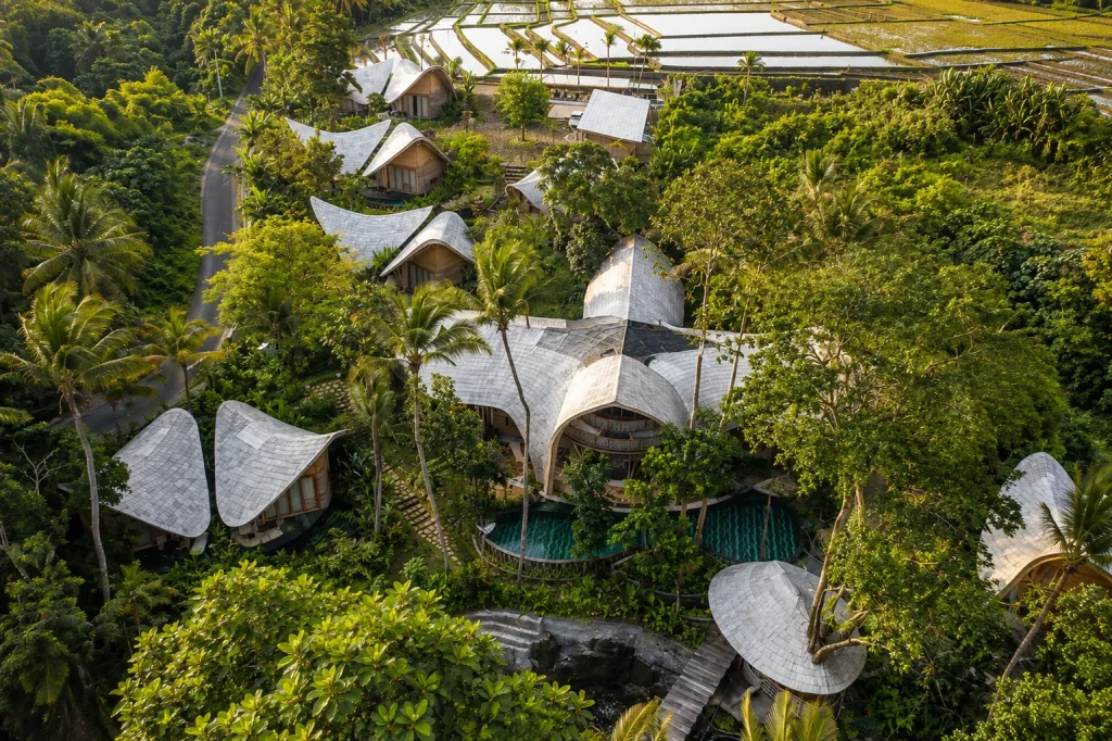 Aerial view of Bali eco resorts like Ulaman, bamboo roofs set against rice terraces