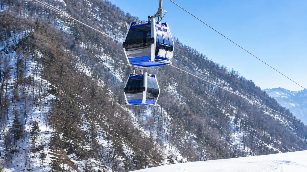 Blue gondolas rising over a snowy forested mountainside on an Azerbaijan ski trip