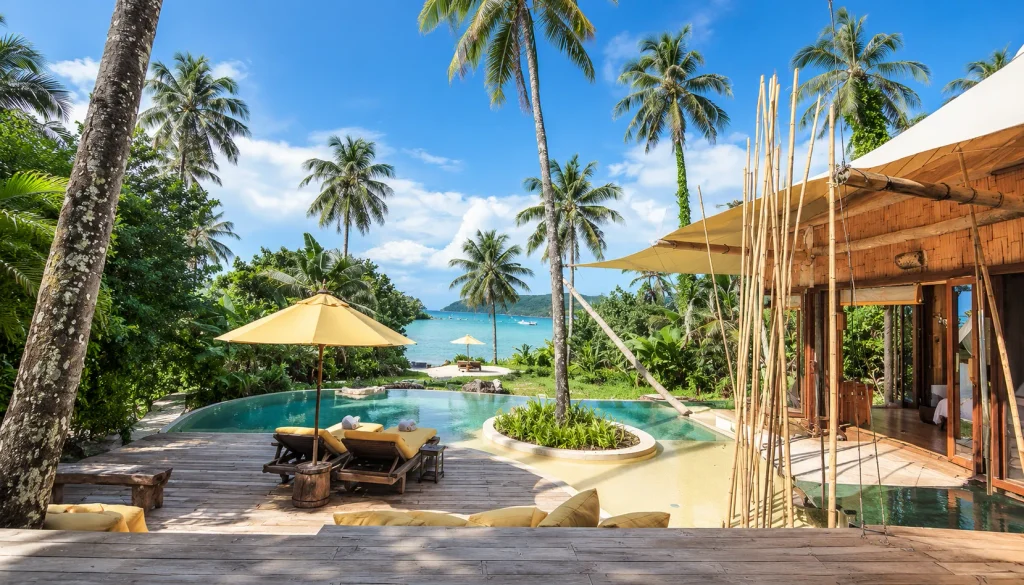 Private pool and sun loungers beside a quiet tropical beach framed by coconut palms, a peaceful family island escape for a thailand december break