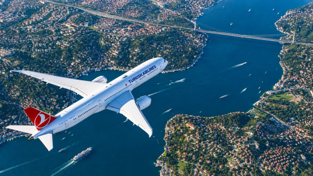 Turkish Airlines jet flying over the Bosphorus Bridge, nonstop from Karachi for Istanbul winter hotels trips